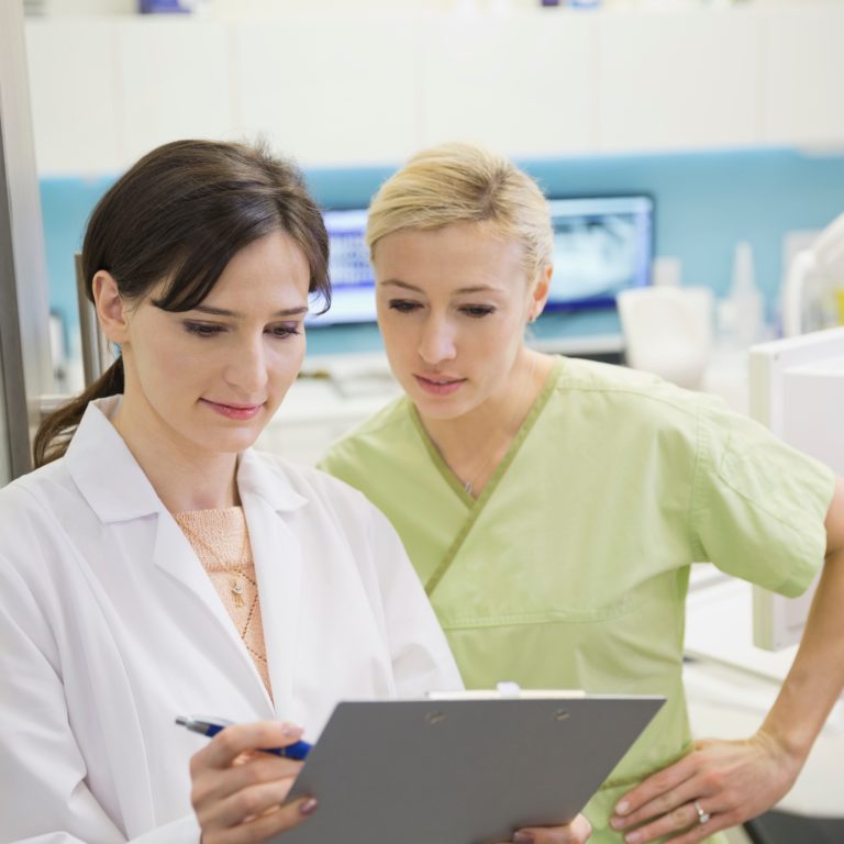 dentist,and,assistant,reviewing,medical,record,in,doorway